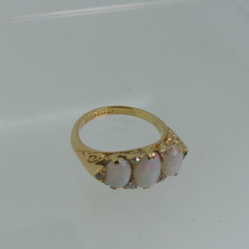 98 - An early 20thC graduated three stone opal Ring, each with two diamond points set vertically  between... 