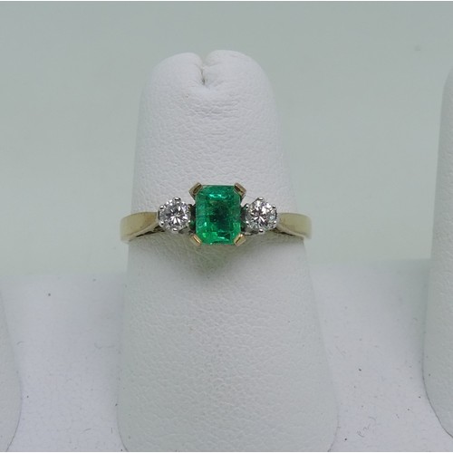 87 - An emerald and diamond three stone Ring, the central emerald cut emerald, c. 5mm x 3.6mm, with a cir... 