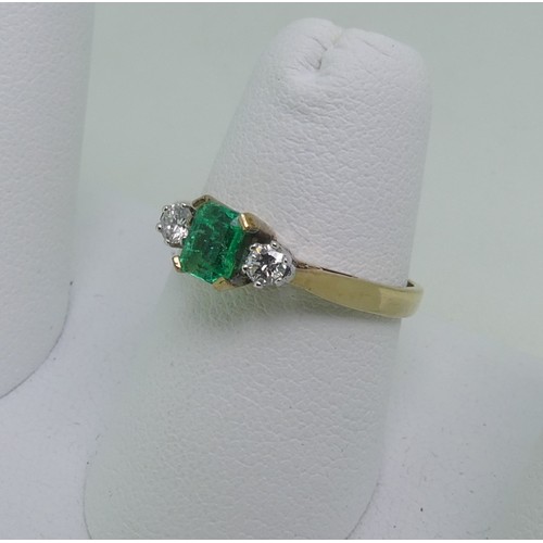 87 - An emerald and diamond three stone Ring, the central emerald cut emerald, c. 5mm x 3.6mm, with a cir... 