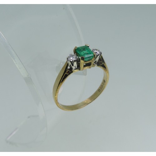 87 - An emerald and diamond three stone Ring, the central emerald cut emerald, c. 5mm x 3.6mm, with a cir... 