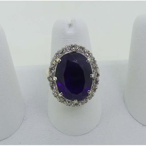 106 - An amethyst and diamond Dress Ring, the oval facetted amethyst surrounded by twenty small diamond po... 