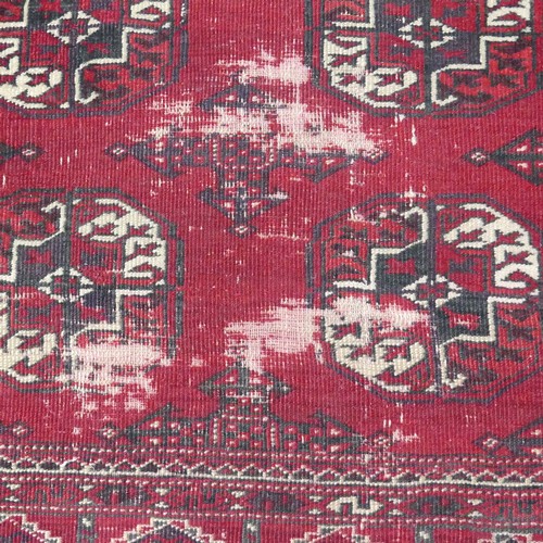 285 - Tribal rugs; a red ground Bokhara rug, worn,  176cm x 118cm.