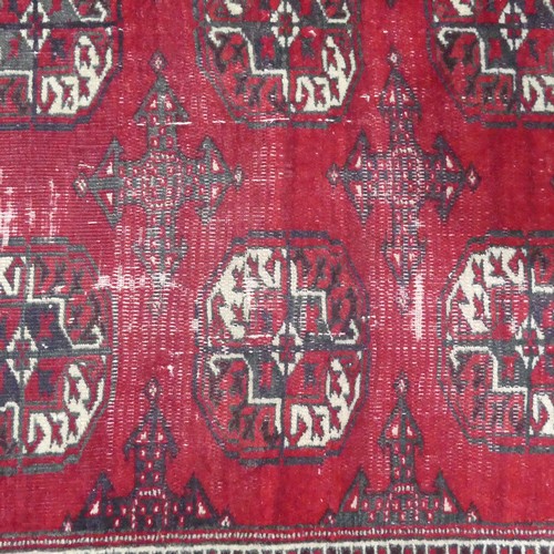 285 - Tribal rugs; a red ground Bokhara rug, worn,  176cm x 118cm.