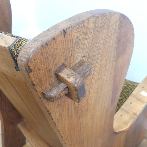 401 - A pair of Arts & Crafts elm 'Lambing Chairs', with shaped back and arm rests, raised upon shaped... 