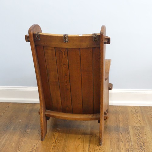 401 - A pair of Arts & Crafts elm 'Lambing Chairs', with shaped back and arm rests, raised upon shaped... 