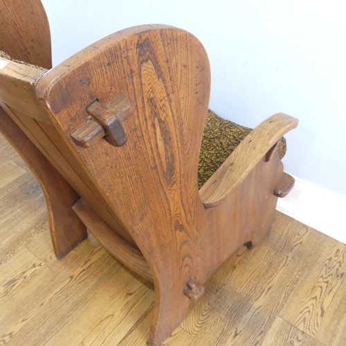 401 - A pair of Arts & Crafts elm 'Lambing Chairs', with shaped back and arm rests, raised upon shaped... 