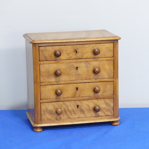 408 - An antique miniature Chest of Drawers, comprising four long drawers, raised on bun feet, some woodwo... 