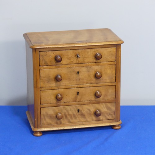 408 - An antique miniature Chest of Drawers, comprising four long drawers, raised on bun feet, some woodwo... 