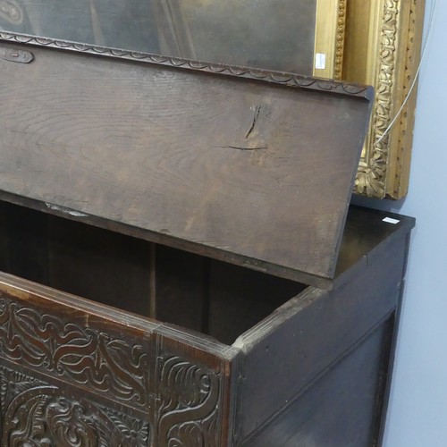 552 - A 17thC carved oak Coffer, the hinged lid opening to a spacious interior, above a three panel front ... 