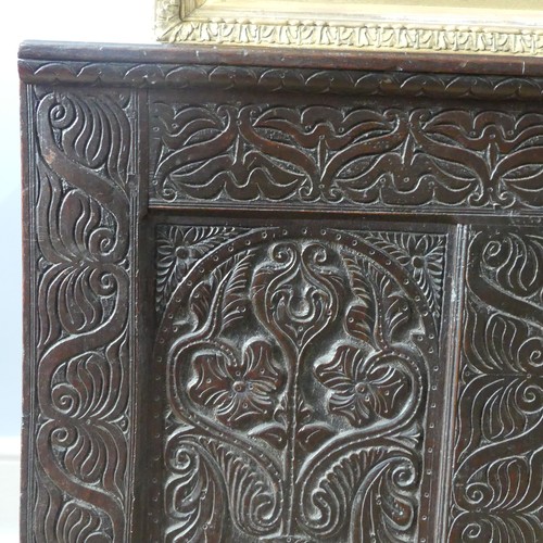 552 - A 17thC carved oak Coffer, the hinged lid opening to a spacious interior, above a three panel front ... 