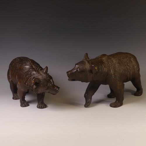 An early 19thC Black Forest carved wooden Strolling Bear, naturistically carved with glass eyes, L 40cm x H 23cm, together with another Black Forest carved Bear, L 37cm x H 21cm, foot broken (2)