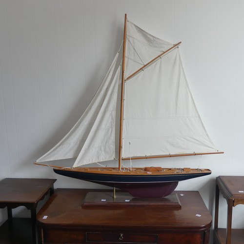 302 - A vintage wooden Pond Yacht, the hull painted in red and blue, with canvas sails and metal fittings,... 