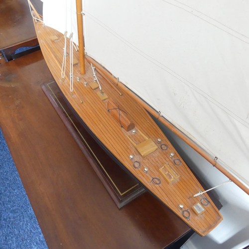 302 - A vintage wooden Pond Yacht, the hull painted in red and blue, with canvas sails and metal fittings,... 