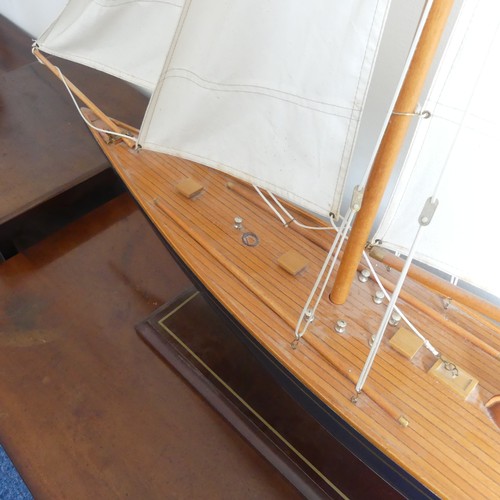 302 - A vintage wooden Pond Yacht, the hull painted in red and blue, with canvas sails and metal fittings,... 