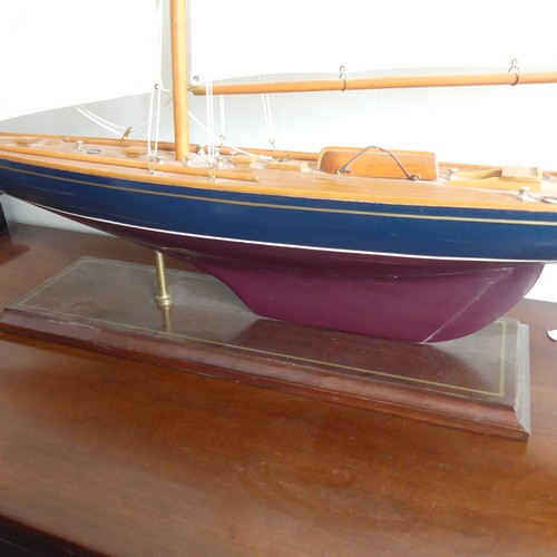 302 - A vintage wooden Pond Yacht, the hull painted in red and blue, with canvas sails and metal fittings,... 