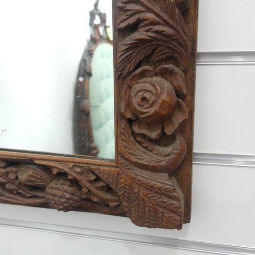 325 - An early 20thC carved oak Wall Mirror, the frame profusely decorated with fruits of the harvest, inc... 