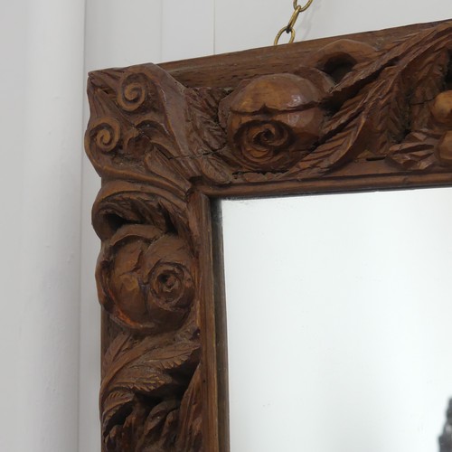 325 - An early 20thC carved oak Wall Mirror, the frame profusely decorated with fruits of the harvest, inc... 