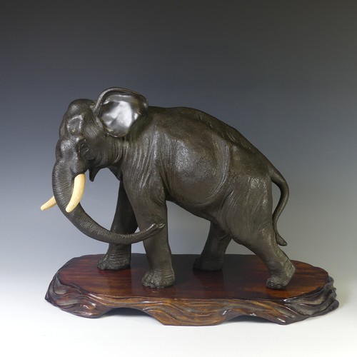 A 19thC Japanese cast bronze figure of an Elephant, cast marching on four feet, head slightly turned to the left, underside with seal mark, on a hardwood stand, H 38cm. DEFRA Ivory Act submission ref: 2KE6YQX9