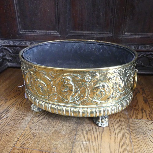 555 - An antique brass Wine Cooler, with embossed decoration of cherubs and leaves, metal lining, brass ca... 