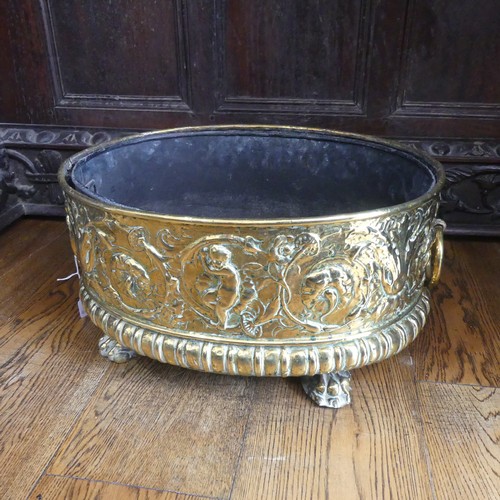 555 - An antique brass Wine Cooler, with embossed decoration of cherubs and leaves, metal lining, brass ca... 