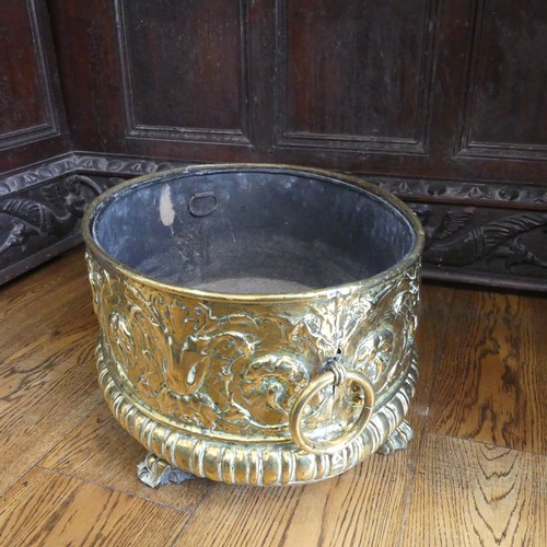 555 - An antique brass Wine Cooler, with embossed decoration of cherubs and leaves, metal lining, brass ca... 