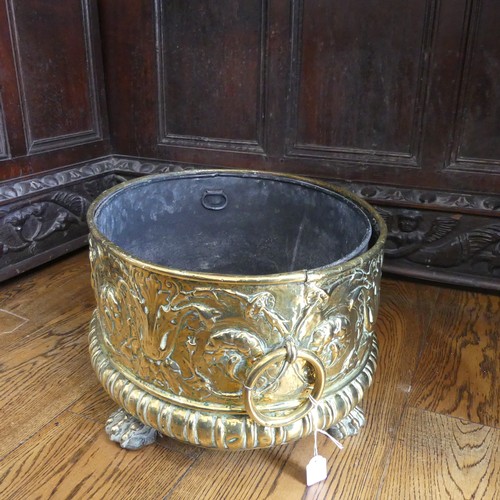 555 - An antique brass Wine Cooler, with embossed decoration of cherubs and leaves, metal lining, brass ca... 