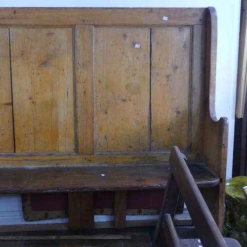 474 - A large antique pine Settle, with panelled back and scrolling end supports, base under the seat need... 