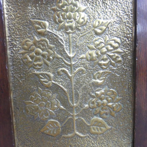 556 - An Arts & Crafts embossed brass and oak Fire Screen, in the manner of John Pearson, decorated wi... 