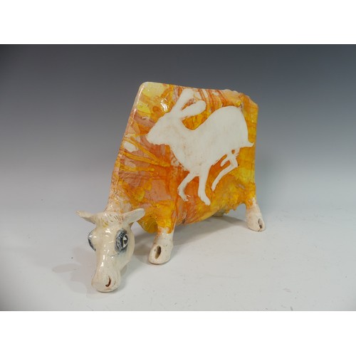 110 - Lawson E. Rudge (b. 1936), a studio pottery sculpture of a Grazing Cow, with orange glazed hare deco... 