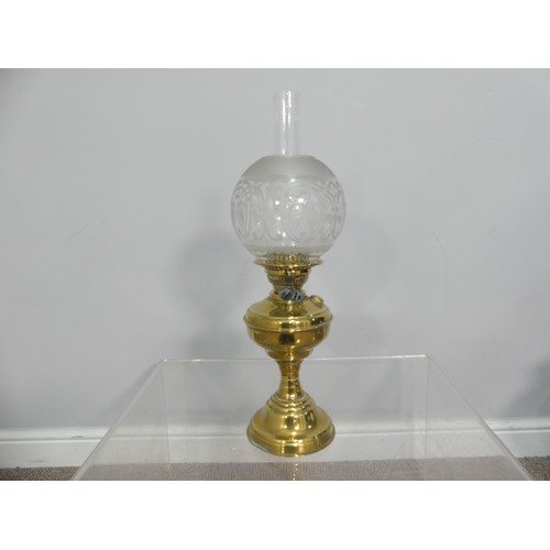 601 - A brass and frosted glass Oil Lamp, the shade with motifs, together with two others similar, tallest... 