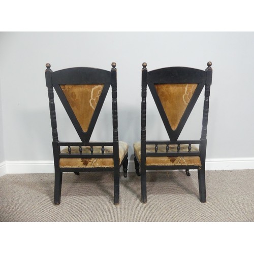 630 - A pair of Arts and Crafts ebonised Chairs, in the manner of Dresser, the carved back with turned spi... 