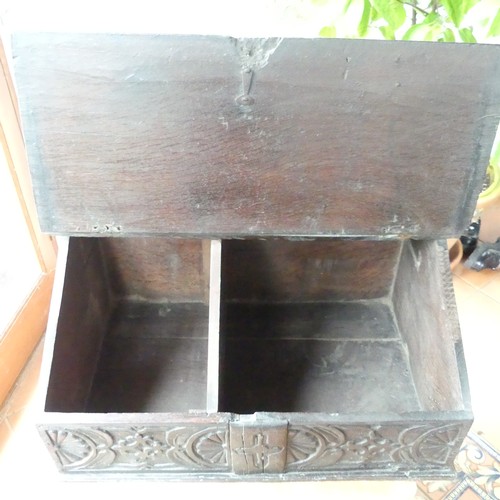 652 - An 18th century oak Bible Box, the sloped lid above a carved frieze, some scuffs, wear and damage to... 