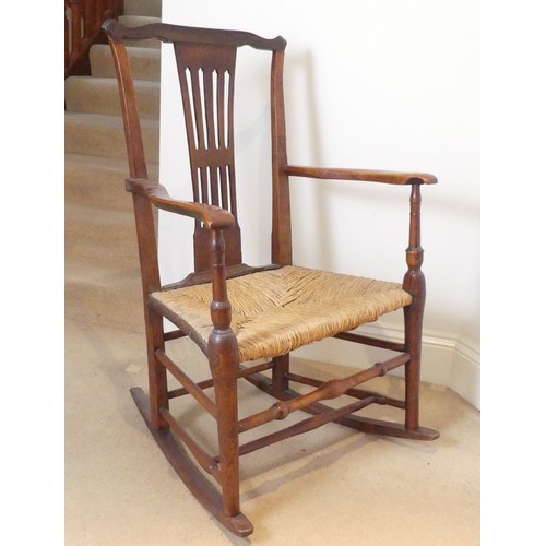 654 - A George III Rocking Chair, having a pierced back above a rush seat, raised on turned legs joined by... 