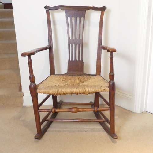 654 - A George III Rocking Chair, having a pierced back above a rush seat, raised on turned legs joined by... 