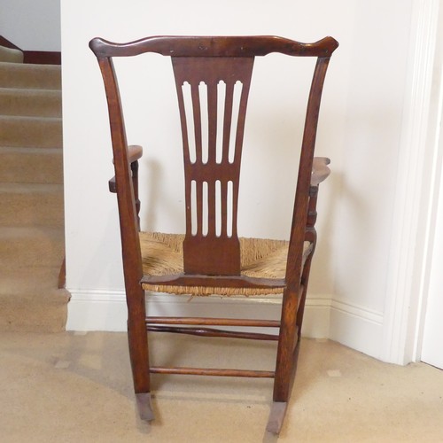 654 - A George III Rocking Chair, having a pierced back above a rush seat, raised on turned legs joined by... 