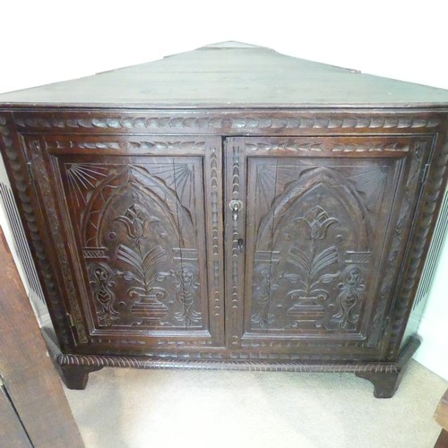 655 - An 18th century oak Corner Cupboard, the two-panel front with carved decoration, probably the bottom... 