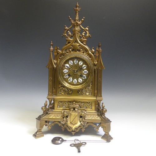 A late 19th century French gilt brass Gothic revival style Mantel Clock, the architectural case with circular dial and ceramic Roman numerals, brass 8-day movement striking on a coiled gong, H: 48cm x W:27cm x D:16cm, with pendulum and key.