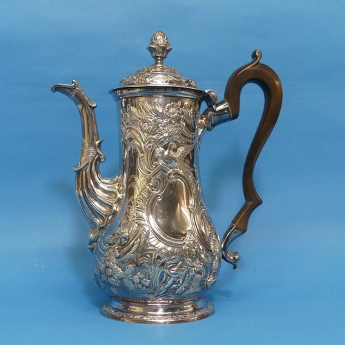 An 18thC Irish silver Coffee Pot, hallmarked for Dublin and with Hibernia mark, no makers mark or date letter, circa 1770, of baluster form profusely decorated in the Rococo style with foliate swags, birds, and figures, pine cone finial, wooden scroll handle, engraved with the Putland (Ireland) Family Crest, 26cm high, approx total weight 33.1ozt.