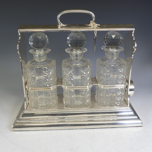 56 - A silver-plated Walker & Hall Tantalus, encasing three cut glass decanters, in a locking 