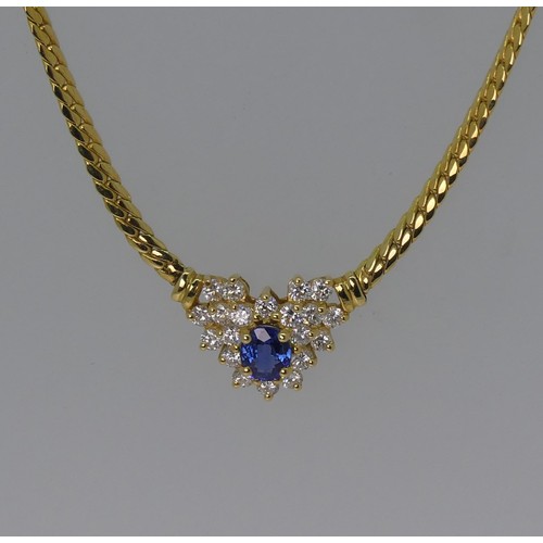 An 18ct yellow gold Necklet, the front set with a sapphire and diamond cluster, the oval facetted sapphire 5.9mm long surrounded by twenty small brilliant cut diamonds, the cluster 15mm wide overall, 42cm long, approx total weight 13.8g.