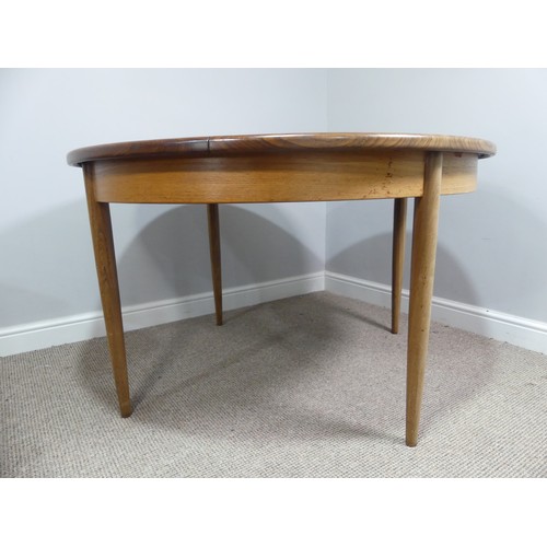 313 - A mid 20thC teak extending Dining Table, of circular form, raised on tapering legs, some scuffs and ... 