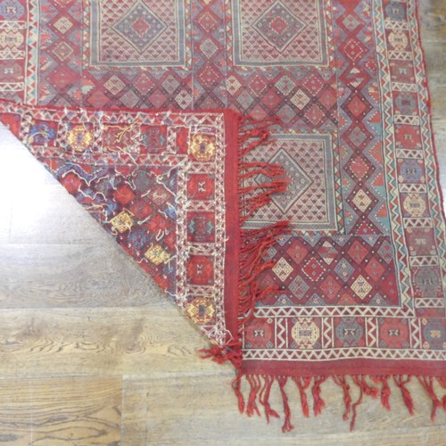 489 - Tribal Rugs; an Afghan rug, tekke on a red ground, 100% wool, fringes worn, 155cm x 183cm, together ... 