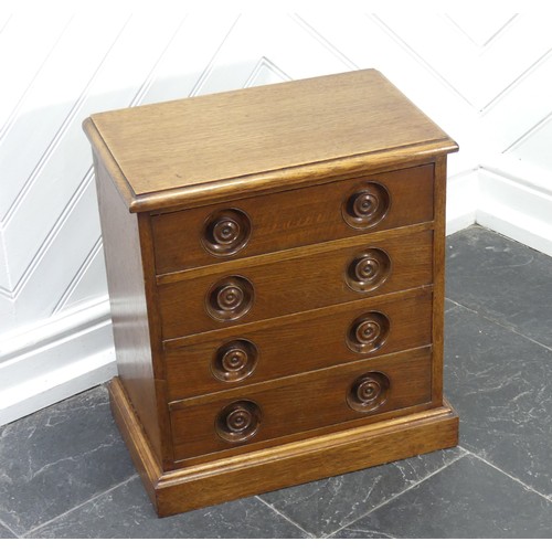 392 - An Arts & Crafts oak four-drawer Stationery Cabinet, of small size with recessed turned handles,... 