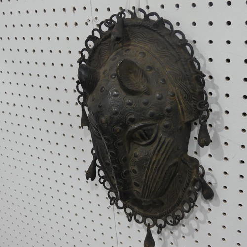 176 - Tribal art; a Benin bronze leopard mask with punched and raised decoration, edged with ring loops an... 