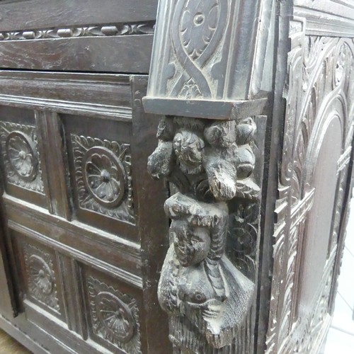 467 - An antique carved oak Cupboard, the front with two panelled doors and caryatid pilasters, both side ... 