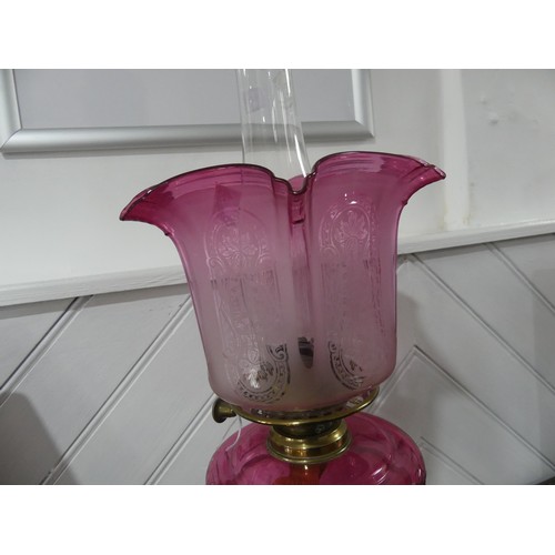 307 - A Victorian brass and cut glass Oil Lamp, having a cut cranberry glass font and etched glass shade, ... 