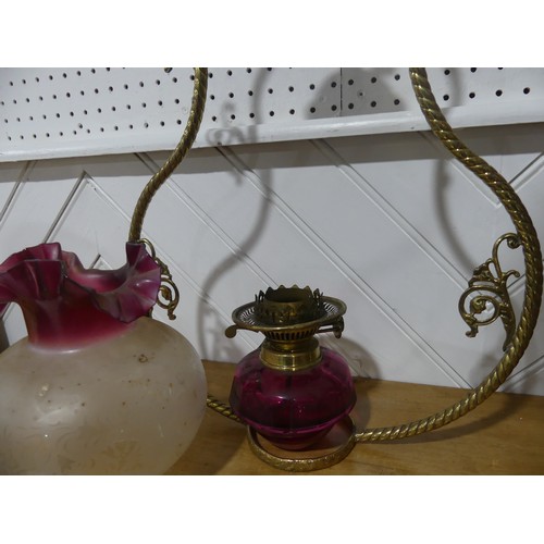 303 - A Victorian hanging brass Oil Lamp, having a cranberry glass font and shade, one brass ornament brok... 