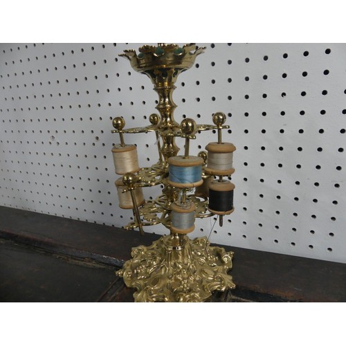 309 - A brass three-tiered Bobbin Holder, decorated with scrolls, fruit and ivy leaves, with pin cushion t... 