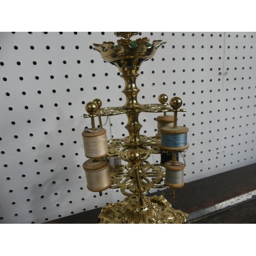 309 - A brass three-tiered Bobbin Holder, decorated with scrolls, fruit and ivy leaves, with pin cushion t... 