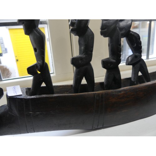 361 - Tribal Art; an African carved wooden 'dug-out' boat with seven standing oarsmen, 61cm long, together... 